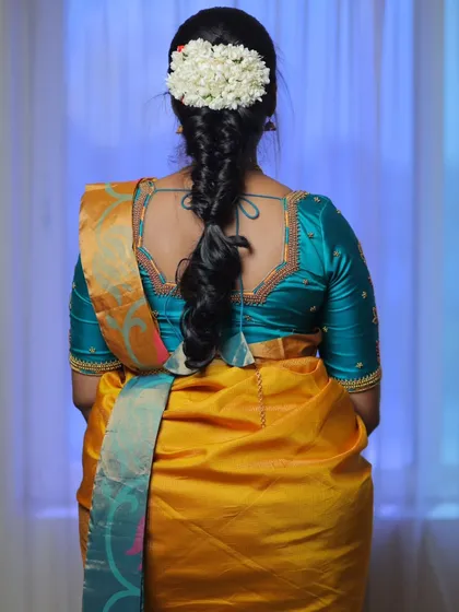 A back view of a baby shower hairstyle. A simple, elegant braid adorned with a string of fresh jasmine flowers.