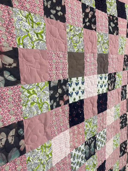 A close-up of the patchwork front of the t-shirt and frock memory quilt, showcasing a variety of patterns and colors.