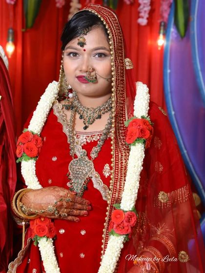 A smiling North Indian bride on her wedding day. The makeup is designed to be long-lasting and vibrant, perfect for the extensive ceremonies.