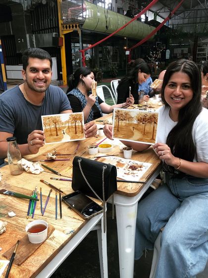 A happy couple showcasing their coffee paintings. My workshops are a great activity for dates, friends, or family to connect and create together.