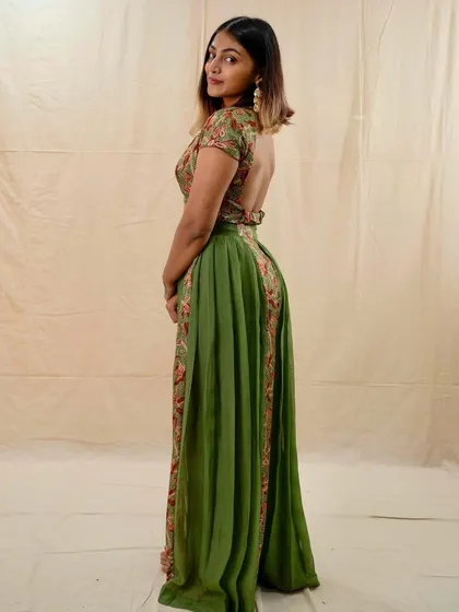 This festive green ensemble features a beautiful backless design with floral embroidery. It's a contemporary Indian outfit that's perfect for someone looking for a unique and stylish festive look.