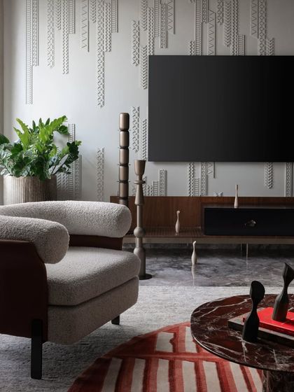 The custom wall paneling in the Scarlet Horizon living room serves as a textured backdrop for the media unit. This detail, combined with the plush boucle armchair and rich red marble coffee table, creates a space that is both dramatic and comfortable.