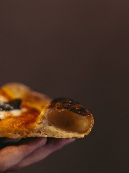 Crust us, it's delicious. A side view of a slice, showing off the puffy, leopard-spotted cornicione, the hallmark of a true Neapolitan pizza.