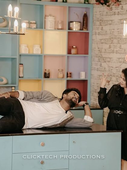 A fun and playful moment on a kitchen counter, with the groom lying down and the bride laughing.