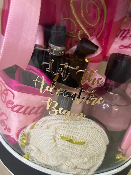 A close-up of the 'Bride To Be' hamper, showing the 'Let The Adventure Begin' detail among the pampering items.