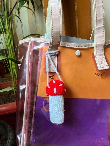 The mushroom lip balm holder attached to a bag, showing how it works as a practical accessory.