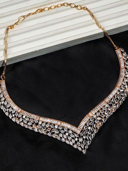 A rose gold and diamond necklace photographed on a black background. The composition highlights the V-shape of the necklace, showing how it would lie when worn.