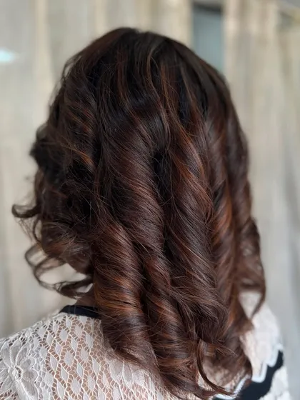 This back view shows the depth and texture created by the curls. The subtle highlights within the brown colour are enhanced by the styling.