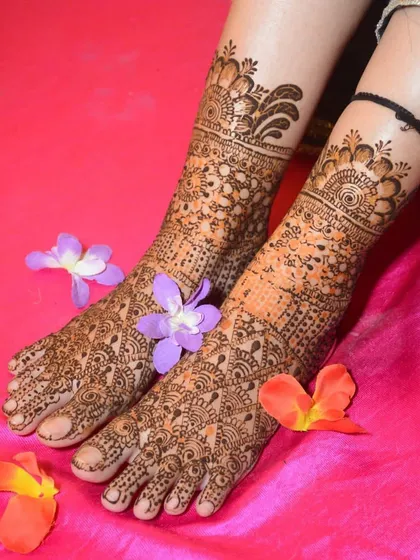 Another shot of the intricate bridal foot mehndi, adorned with flower petals. The design is dense, detailed, and perfect for a bride's special day.
