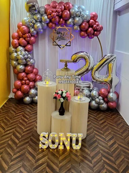 A 24th birthday setup with a rose gold and silver balloon arch. Large silver foil numbers and light-up name letters complete the look.