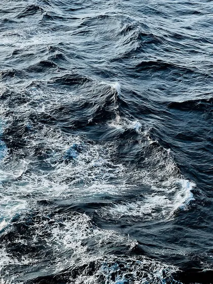 An abstract, detailed shot of the deep blue ocean waves, capturing the texture and power of the sea.