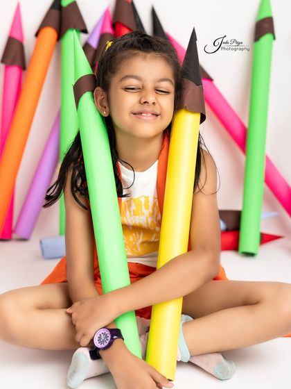 A sweet, happy moment hugging the colorful pencil props. This image radiates pure, simple joy.