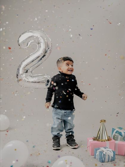 Two years of fun. This energetic shot captures the pure joy of a second birthday, with confetti flying and a big smile on the birthday boy's face.