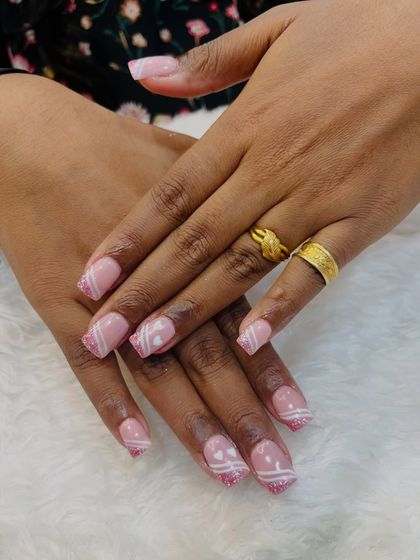 A pretty and feminine design on extensions. This set features a soft pink base with glitter and delicate white line art, including some cute hearts.