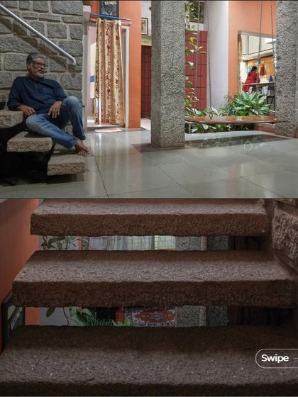 The iconic cantilevered stone staircase at the Rehmat Tarikere Residence. Each step is a solid block of stone inserted into the wall, creating a floating effect that is both strong and elegant.