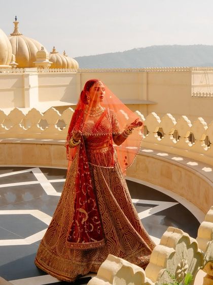 Bride Shree looking ethereal in her red Tarun Tahiliani wedding lehenga. The sheer veil and the stunning backdrop create a truly magical moment.
