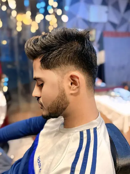 A classic taper fade haircut. The hair is gradually faded down the sides and back, leaving more length and volume on top for styling.