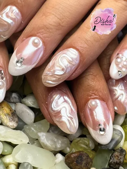The beauty of pearls on nails. This design features a swirling, pearlescent texture accented with carefully placed pearls and rhinestones for a look of pure elegance.