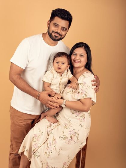 A classic studio family portrait. The parents' are holding their baby, creating a timeless image of their new family unit.