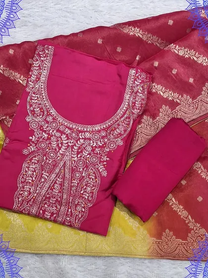 A bright and cheerful dress material set with a pink top and a yellow and red Banarasi dupatta. The intricate embroidery on the top adds a festive touch.