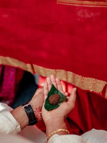 A close-up of hands during a wedding ritual, symbolizing the union and blessings being exchanged.