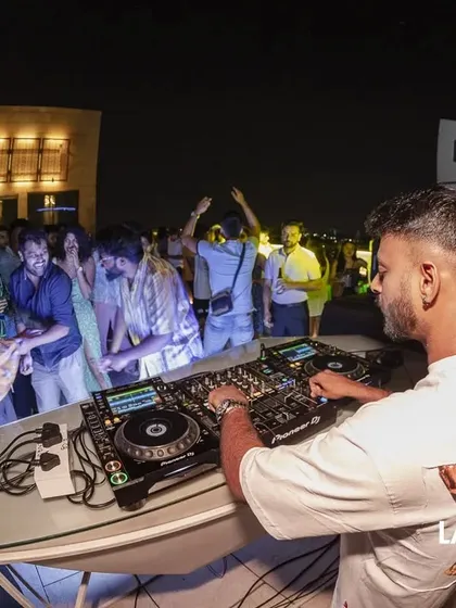 A fisheye lens perspective of me at the decks, capturing the dynamic energy of the dancing crowd and the rooftop venue.