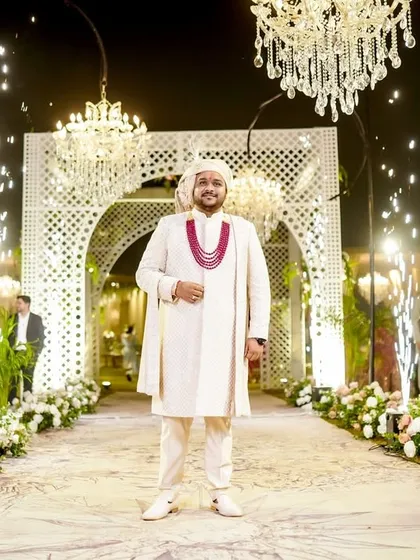 The groom stands at the entrance of the beautifully decorated wedding venue, looking regal and ready for his grand entry.