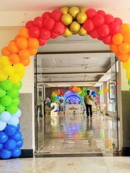 A vibrant rainbow balloon arch at the entrance of a banquet hall, perfect for a colorful Cocomelon or carnival-themed party.