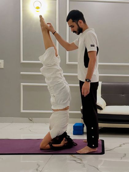 Here, I'm providing support for a student's Sirsasana (Headstand). My guidance helps with balance and alignment, making inversions accessible and safe even if you are a beginner.