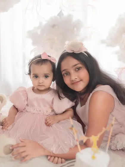 A classic portrait of two sisters. They are dressed in matching pink tulle dresses for this dreamy, cloud-themed first birthday shoot.