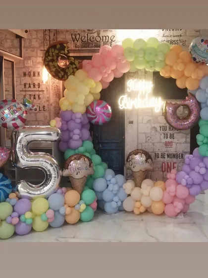 A sweet and colorful candy-themed 5th birthday. We used a full circle of pastel balloons and added fun foil balloons shaped like donuts, ice cream, and candy to bring the theme to life.
