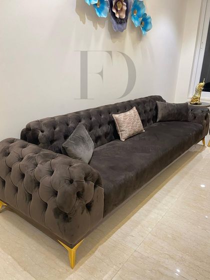 A classic Chesterfield sofa in a deep charcoal velvet, featuring deep button-tufting and elegant scrolled arms. This timeless piece adds a touch of traditional luxury to any modern interior.