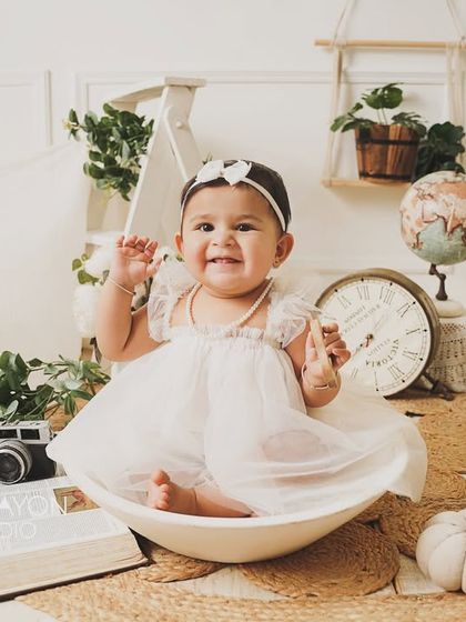 A big, happy wave from the birthday girl during her all-white, bohemian-style first birthday shoot.
