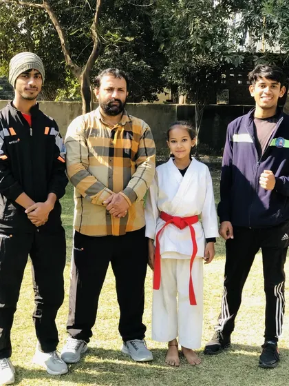 A young female red belt with the coaching team. She is a testament to the fact that karate is for everyone.