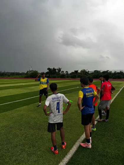 A group of our residential players listen intently to a coach's instructions on the pitch. The dramatic sky and expansive field highlight the inspiring setting where our athletes train.