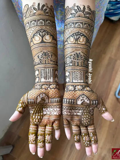 A beautiful engagement mehendi featuring elegant peacocks and swans, with intricate patterns filling the hands and arms.