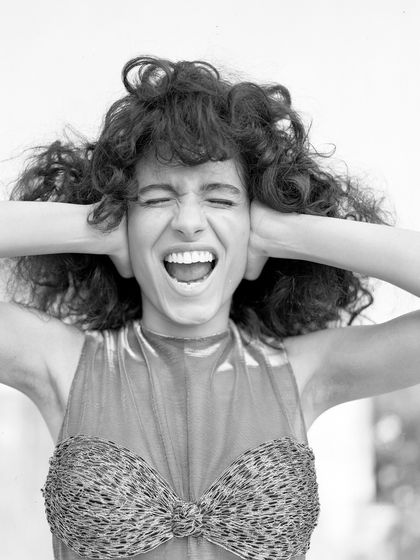 An expressive black and white shot from an archival project. The model's joyful scream and the textured top create a feeling of raw energy and freedom.