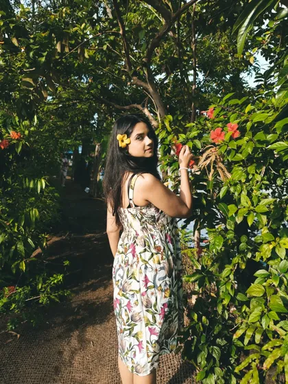 Posing among the beautiful greenery in Kerala. The print of the dress echoes the surrounding nature, creating a cohesive and aesthetically pleasing vacation photo.