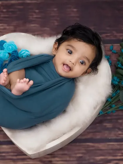 A happy and awake newborn, swaddled in a teal wrap and peeking out from a heart-shaped bowl. Capturing these alert moments is just as special as the sleepy ones.