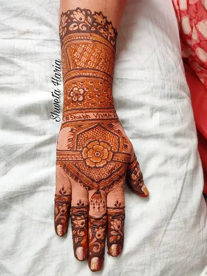 A classic back-hand design with 'Shubh Vivah' (Happy Wedding) written on the wrist. This style, featuring a central floral hexagon and patterned bands, is a timeless choice for wedding guests.