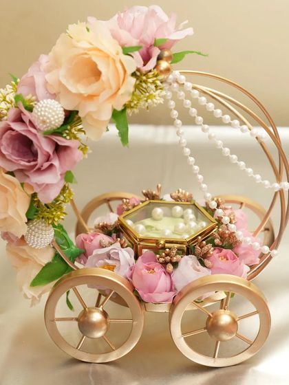 A front-facing view of the "Ring on Wheels" platter, showcasing the delicate pastel flowers, pearl strings, and the hexagonal glass box for the rings. Available for rent.