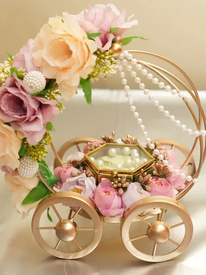 A front-facing view of the "Ring on Wheels" platter, showcasing the delicate pastel flowers, pearl strings, and the hexagonal glass box for the rings. Available for rent.