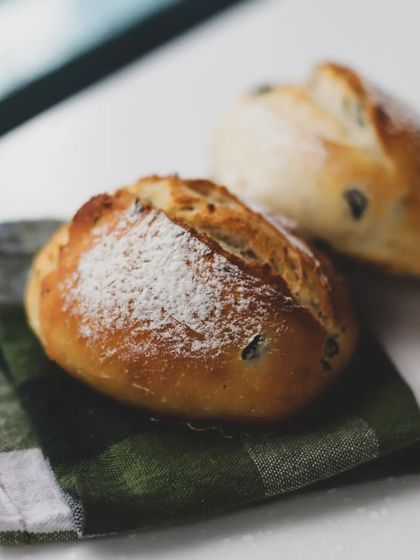 Rustic olive bread rolls, dusted with flour. We explore different types of doughs and additions in our bread-making classes.