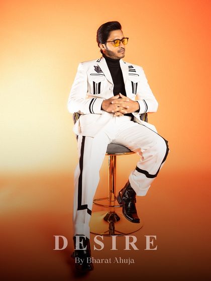 Command the room without saying a word. This seated pose in the white and black striped suit exudes an air of cool, retro authority.