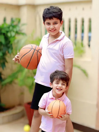 Childhood is about play and shared laughter. This outdoor sibling portrait captures the fun and energy between two brothers, just being themselves with their basketballs.