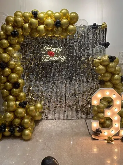 A glamorous 31st birthday with a silver and gold theme. A sequin wall is framed by a gold balloon arch, with large light-up numbers adding to the sparkle.