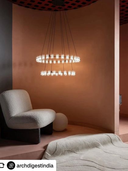 Another view of the tiered ring chandelier, this time showing how it illuminates a seating area. The soft glow on the textured walls enhances the warm, inviting atmosphere of the showroom.