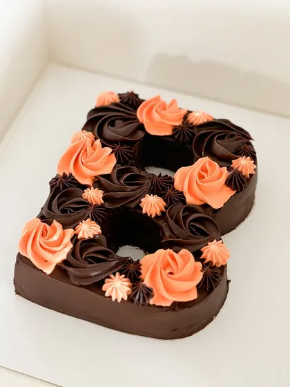 Sweeten up your feed with this delicious monogram chocolate cake. This "B" is decorated with rich chocolate and beautiful orange-colored rosettes, and it's available in a vegan version too.