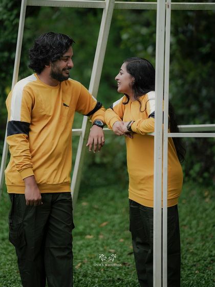 The couple leaning against a white frame, sharing a look and a smile in a moment of easy companionship.