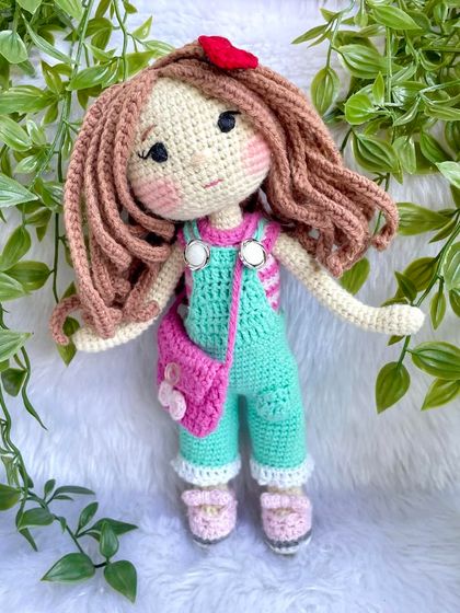 This is the same doll in her second outfit! This set includes mint green overalls, a pink floral bag, and a cute red hair clip. Having multiple outfits makes playtime even more exciting.